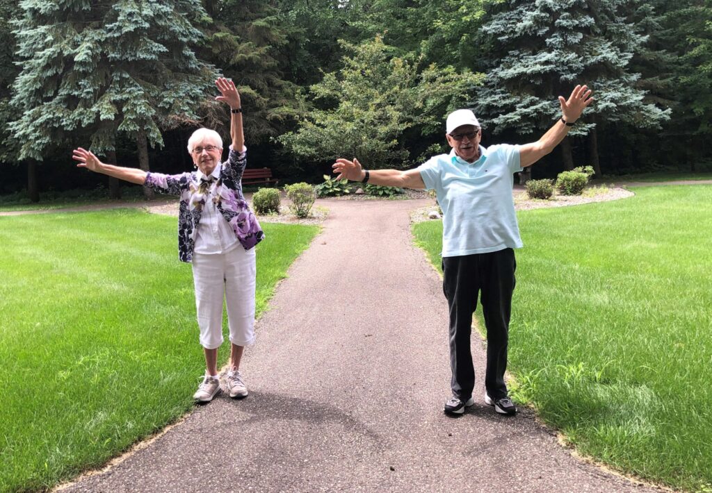 Image of two residents stretching while practicing COVID-19 restrictions of being 6 feet apart